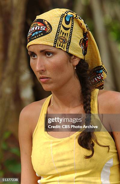 American reality tv show participant Julie Berry, dressed in a yellow tank top and matching yellow 'Survivor' scarf, stands and watches during an...