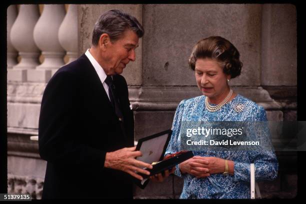 Queen Elizabeth II presents the US President Ronald Reagan with an honoury Knighthood on on June 14, 1989 at Buckingham Palace in London.