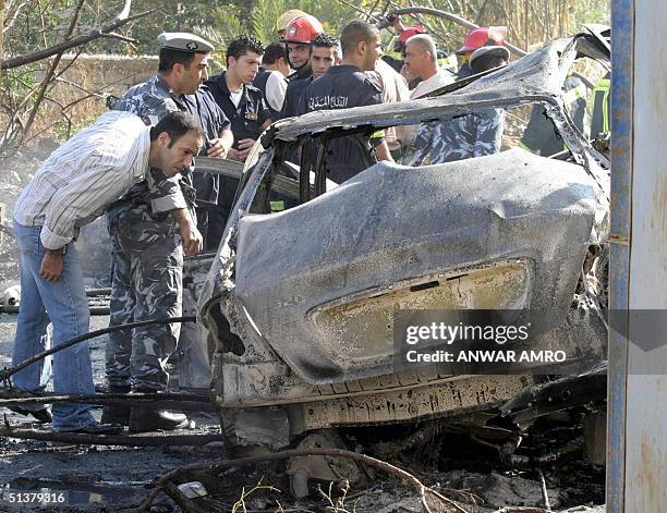 Lebanese policemen inspect the car of outgoing Economy and Trade Minister Marwan Hamadeh after it was targeted by a bomb in Beirut 01 October 2004....