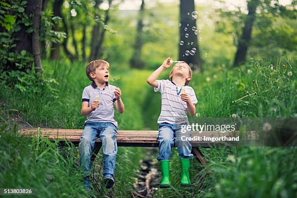 kleine bruder " blasen blasen auf einer kleinen brücke im wald - child bubble stock-fotos und bilder