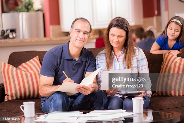 latin descent couple paying monthly bills at home. - social projects address needs of struggling families stockfoto's en -beelden