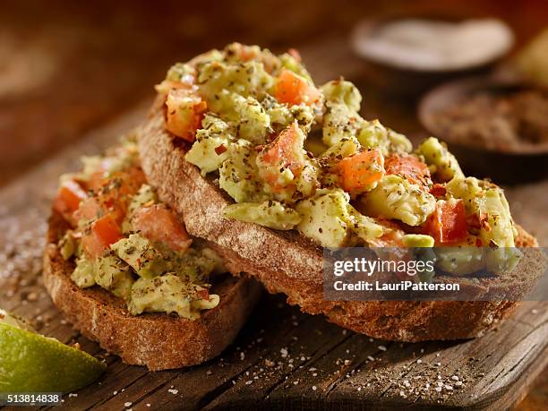 avocado toast with tomatoes on rye bread - toasted sandwich stockfoto's en -beelden