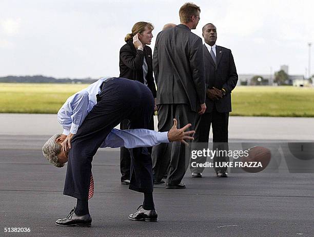 Democratic presidential candidate John Kerry hikes a football as US Secret Service agents stand behind at Tampa International Airport in Tampa,...