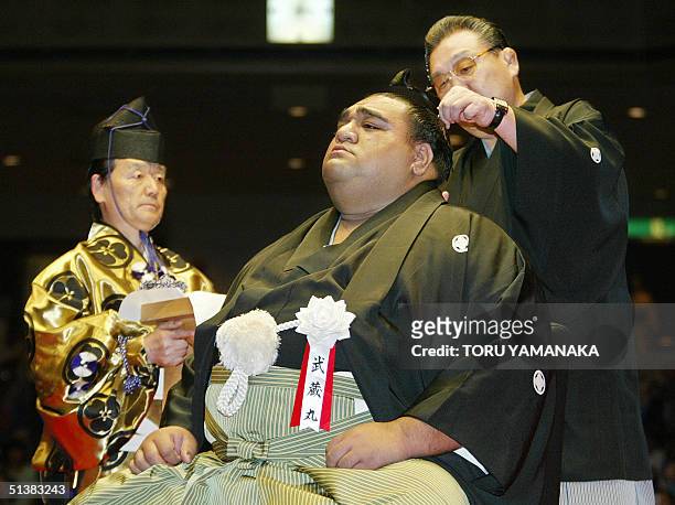 Stable master Musashigawa tries to cut a topknot of former grand champion, or yokozuna, Musashimaru by scissors while head sumo referee Inosuke...