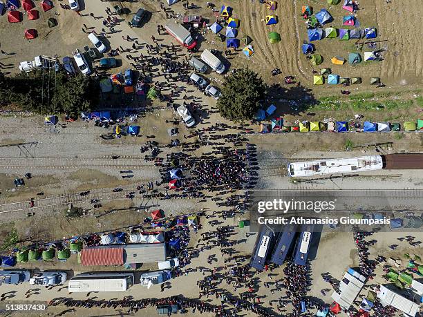 Aerial view of refuges stands in front of police officers as a train attempts to pass at the Greek- FYROM border on March 03, 2016 in Idomeni,...