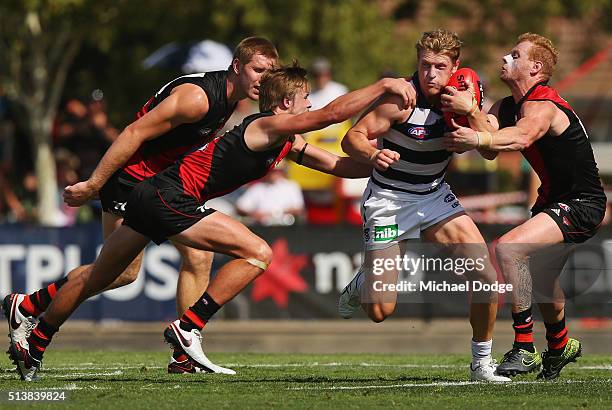 Josh Caddy of the Cats runs with the ball through Martin Gleeson and Adam Cooney of the Bombers during the 2016 AFL NAB Challenge match between the...