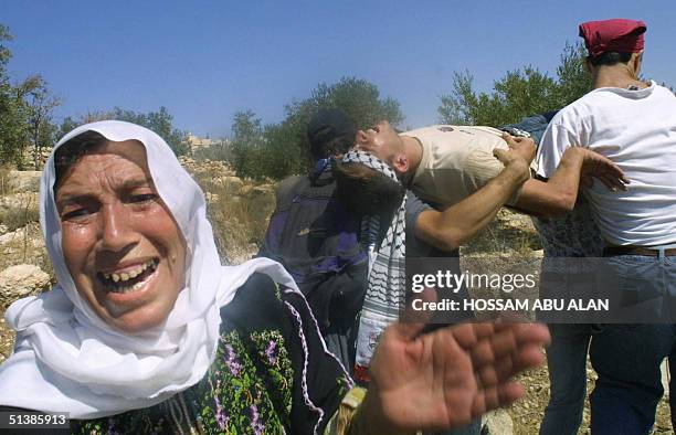 Palestinian woman expresses her anger while an injured Palestinian is evacuated following clashes with Israeli soldiers near the West Bank village of...