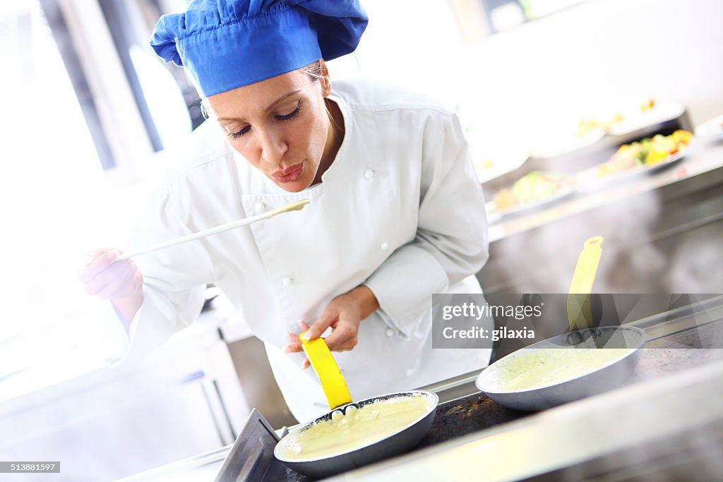 Female chef tasting food.