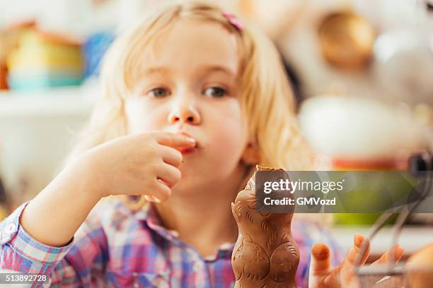 niedlich kleines mädchen essen schokolade osterhasen - osterhase schokolade stock-fotos und bilder