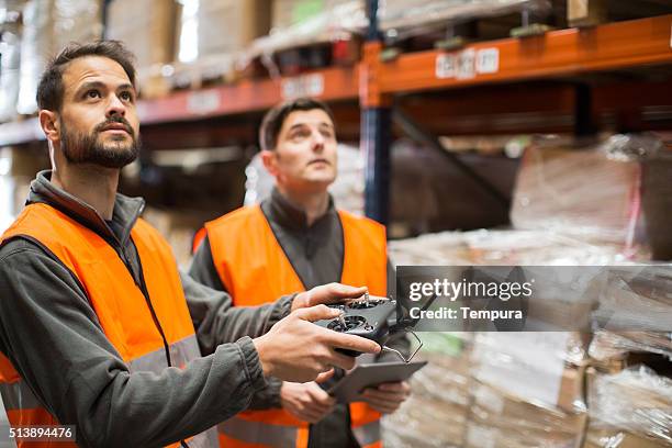 piloting a drone inside a warehouse. - radio controlled handset stock pictures, royalty-free photos & images