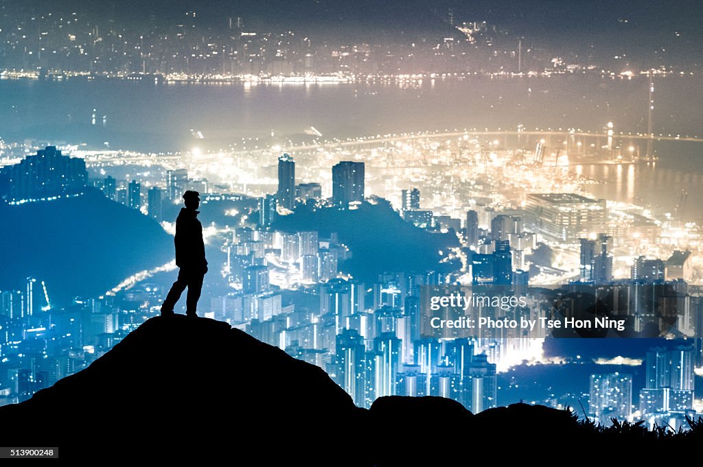 Silhouette of standing hiker with hong kong city urban night view