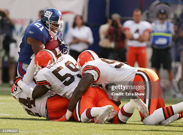 Tiki Barber of the New York Giants is tackled by Robert Griffith, Kevin Bentley and Kennard Lang of the Cleveland Browns at Giants Stadium on...