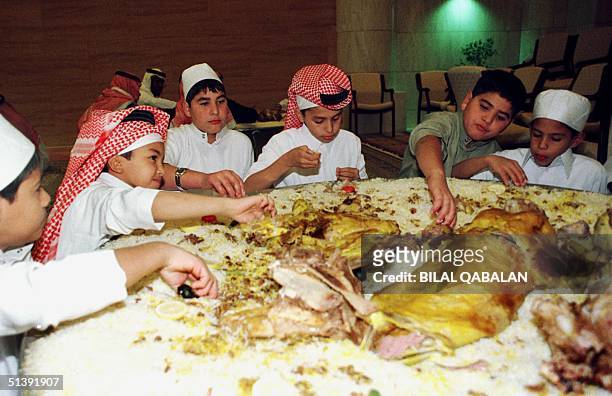 Saudi boys eat the traditional Eid al-Fitr dish, stuffed lamb with saffron rice, nuts and spices, after prayers at Riyadh's Grand mosque 16 December...