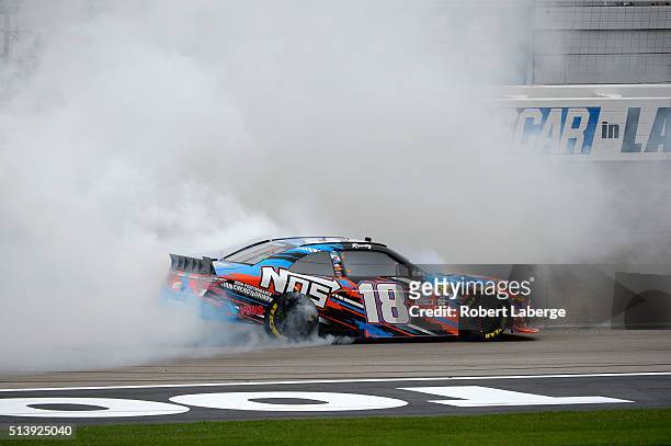 Kyle Busch, driver of the NOS Energy Drink Toyota, does a burnout after winning the NASCAR Xfinity Series Boyd Gaming 300 at Las Vegas Motor Speedway...