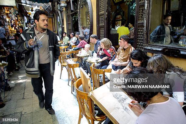 An Egyptian street vendor looks at art students sketching as they sit at the traditional cafe of al-Fishawi in Cairo's historical Khan al-Khalili...