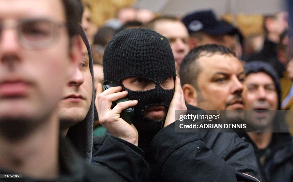 A masked protester talks to other demonstrators on