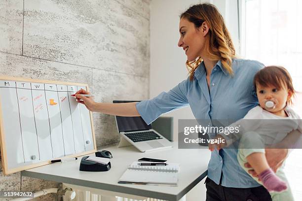 mother working from home and holding her baby - day planner bildbanksfoton och bilder