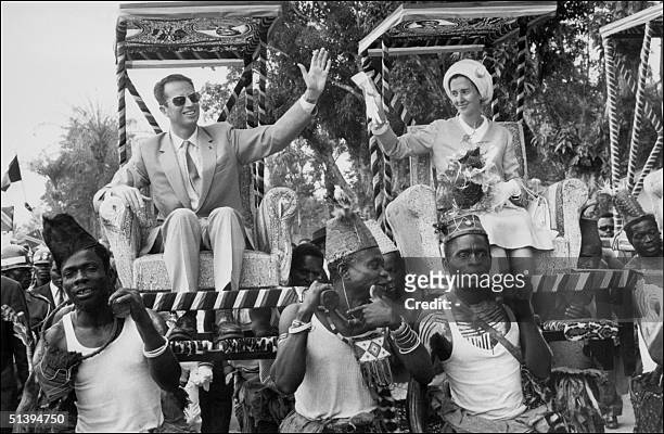 King Baudouin of Belgium and his wife Queen Fabiola wave to wellwishers as they are carried 26 June 1970 in the armchairs during their trip to...