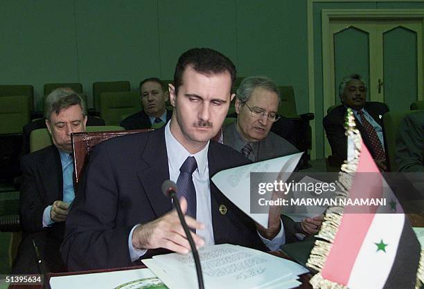 Syrian President Bashar al-Assad reads a document at the start of the third and last session of the Arab summit in Cairo 22 October 2000. On right is...