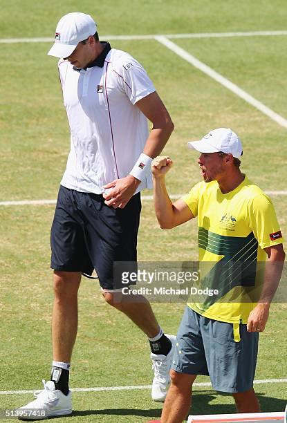Australian Captain Lleyton Hewitt celebrates next to John Isner of the USA as Bernard Tomic of Australia wins the third set in his match against John...