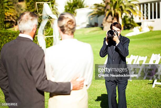 man photographing mature couple at outdoor wedding - heteroseksueel koppel stockfoto's en -beelden