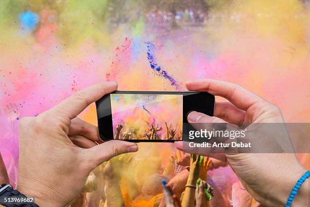 man taking pictures from personal point of view with smartphone during the colorful celebration of the holi festival with colorful powder. - personal perspective festival stock pictures, royalty-free photos & images