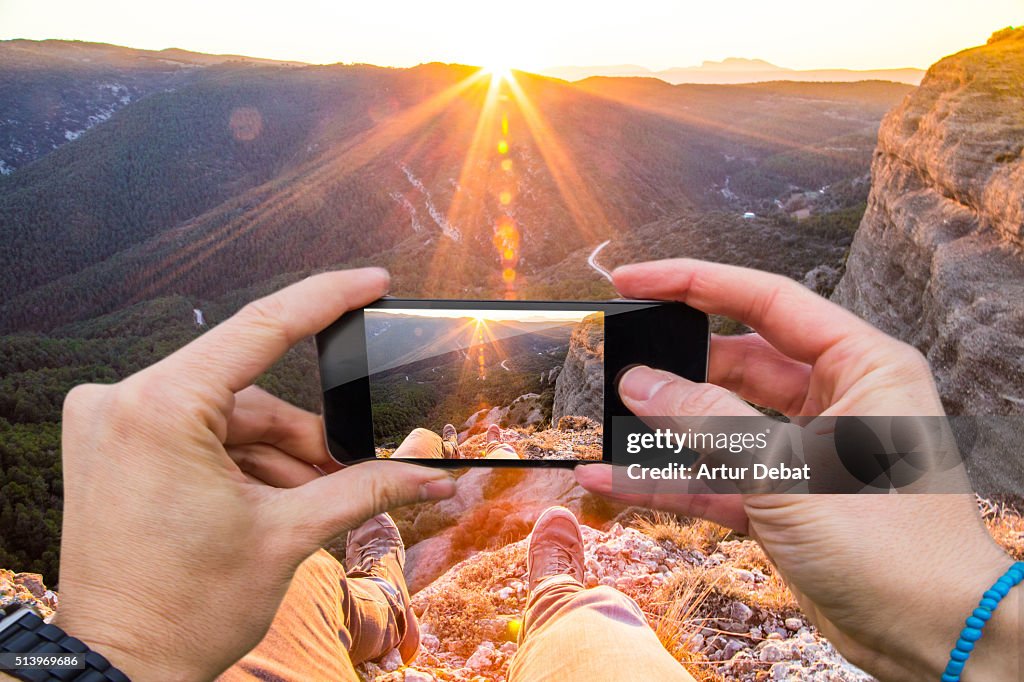 Man taking pictures from personal point of view with smartphone of the stunning landscape on sunset in the Catalan Pyrenees.