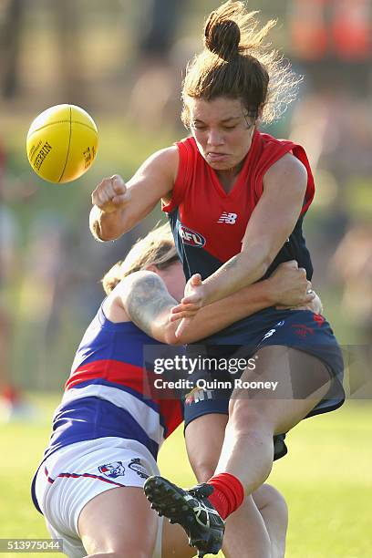 Ellie Blackburn of the Demons handballs whilst being tackled by Hannah Scott of the Bulldogs during the Women's AFL Exhibition Match between the...