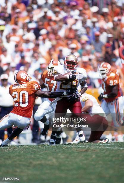 Running back Warrick Dunn of the Florida State Seminoles runs with the ball as Brian Dawkins of the Clemson Tigers goes for the tackle on September...