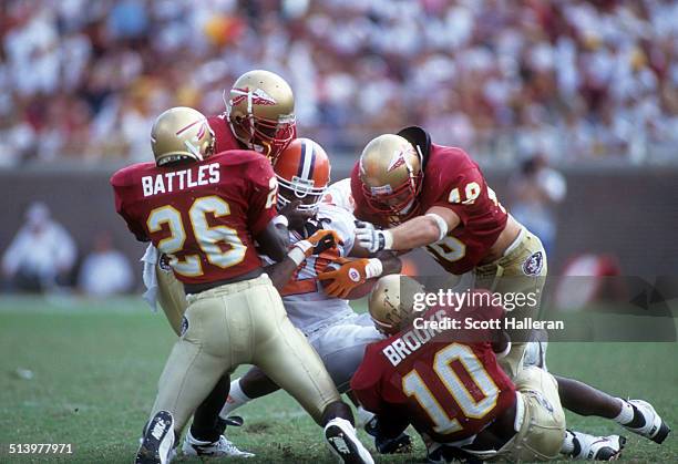 Harold Battles, Derrick Brooks, Todd Rebol and Richard Coes of the Florida State Seminoles tackle an unidentified player from the Clemson Tigers on...