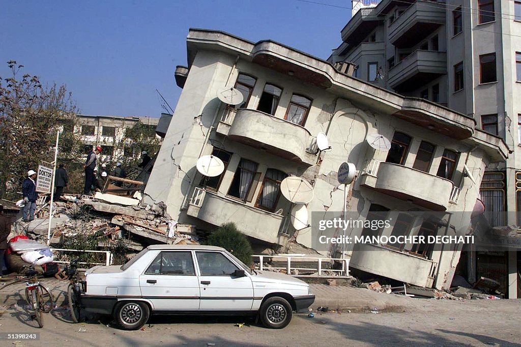 A car is parked in front of a destroyed building i