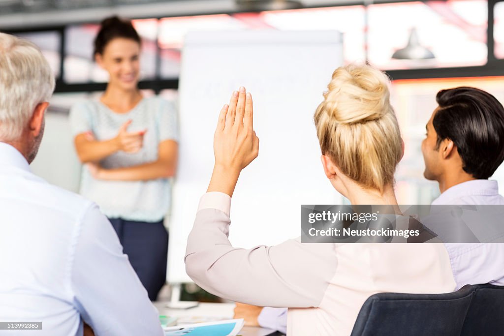 Businesswoman Raising Hand To Answer During Seminar