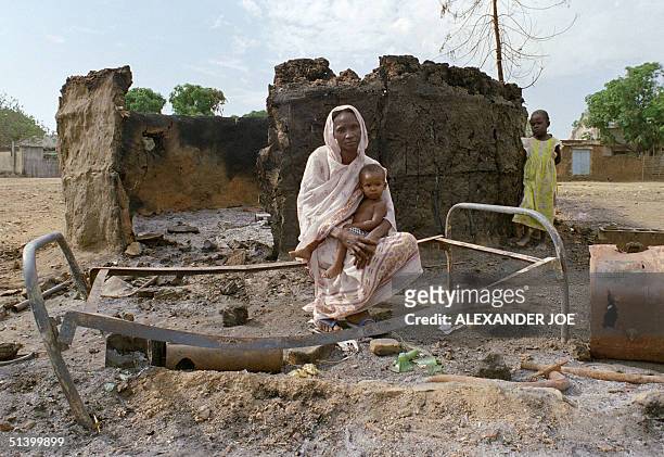 Sudanese woman with her baby sits 12 mars 1989 on a bed frame in Juba village after her hut was set on fire during a Sudan people's Liberation Army...