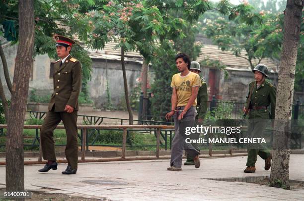 Handcuffed man is led by Chinese soldiers on a street in Beijing 14 June 1989 as police and soldiers keep searching people involved in April-June...