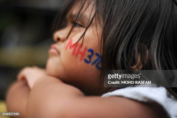 Boy with his face painted with the missing Malaysia Airlines ill-fated flight MH370 logo looks on during a memorial event in Kuala Lumpur on March 6,...