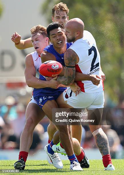 Lin Jong of the Bulldogs handballs whilst being tackled by Nathan Jones of the Demons during the 2016 AFL NAB Challenge match between the Western...