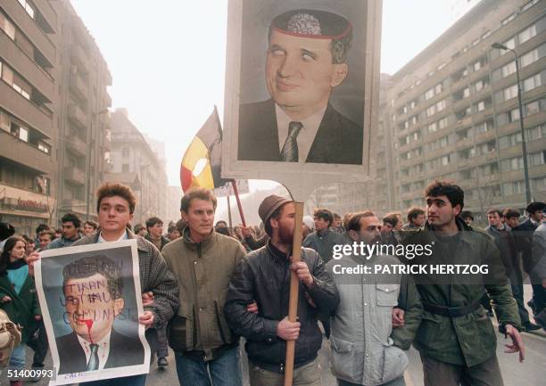 Anti-Communist civilians hold anti-Ceausescu portraits 25 December 1989 in downtown Bucharest as the anti-Communist uprising to end Nicolae...