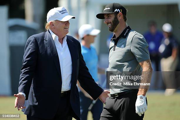 Republican presidential candidate Donald Trump makes an appearance prior to the start of play and speaks with golfer Dustin Johnson on the range...