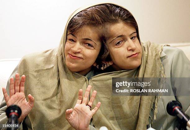 Iranian sisters Laleh and Ladan Bijani , joined by the head, smiles during a press conference at the Raffles Hospital in Singapore, 03 December 2002....