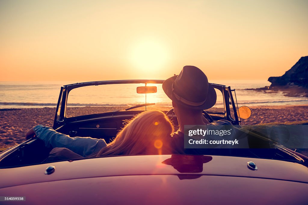 Paar beobachten den Sonnenuntergang in einem Cabrio Auto.