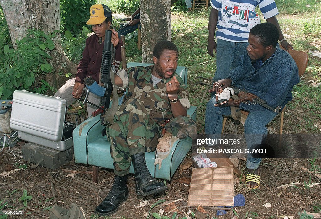 Rebel leader Charles Taylor (C) speaks with troops