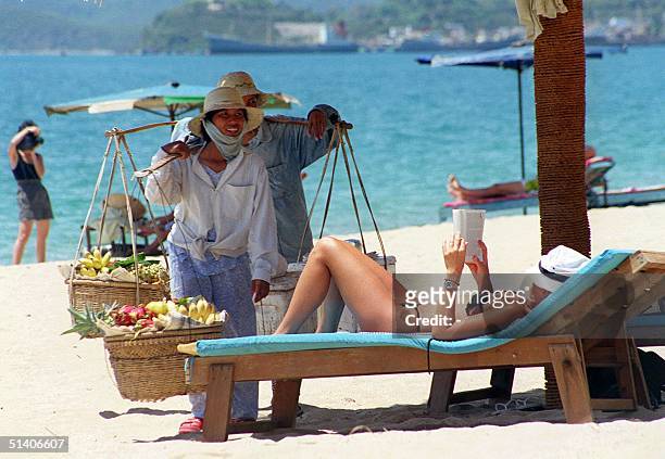 Fruit vendors approach a foreign tourist taking a sunbath on a beach in the central coastal city of Nha Trang 21 June. According to official figures,...