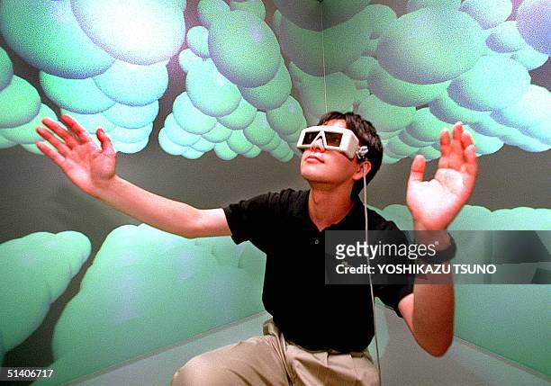Hiroaki Yano, a researcher of the Tokyo University's Intelligent Modeling Laboratory with a 3-D glasses, extends his hands to touch carbon atoms as...