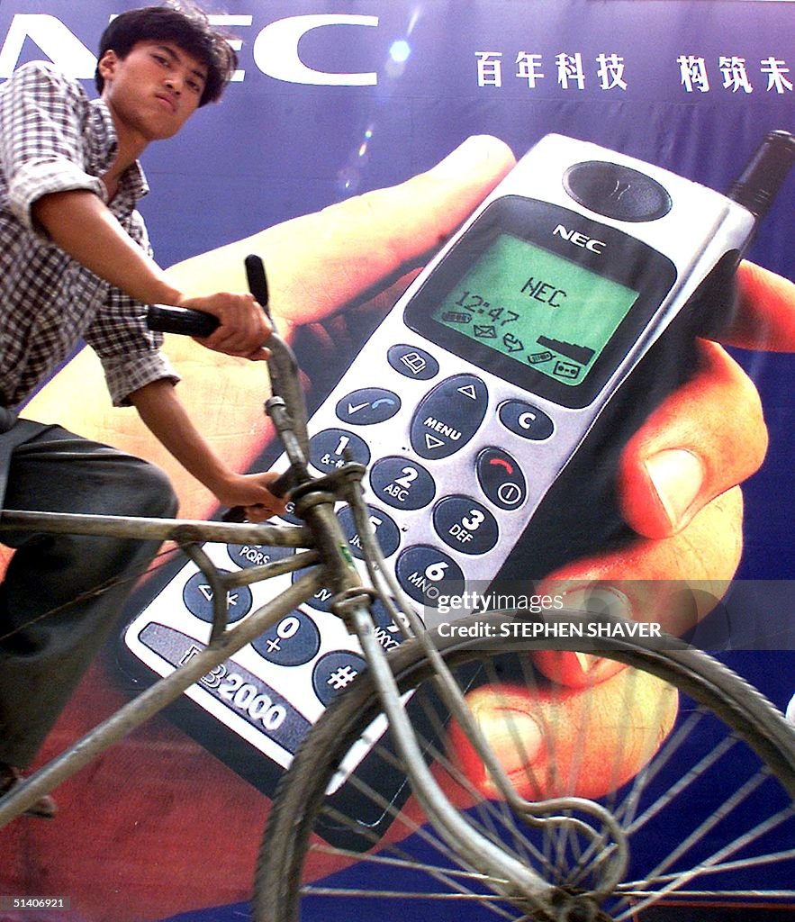 A young pedicab driver cycles past a giant poster