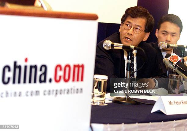 The chief executive officer of china.com Corp, Peter Yip , is flanked by David Kim , chief financial officer, as he announces second quarter results,...