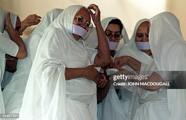 Jain nuns dab themselves with water used to wash an elder priest during a Jain ordination ceremony 19 September 1999. Jainism, founded some 2.500...