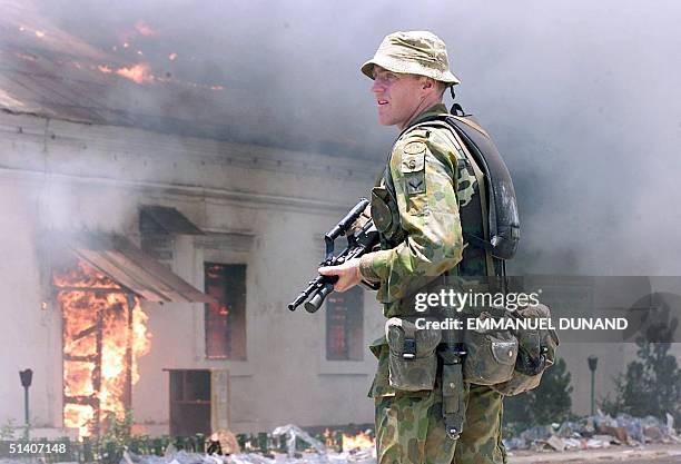An Australian soldiers keeps his weapon at the ready in front of a blazing building 29 September 1999 after the fire set by unknown arsonists erupted...