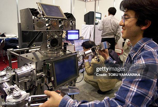 Waseda University student Kuniaki Noda dances with new robot "WAMOEBA-2R" during the '99 International Robot Exhibition in Tokyo, 26 October 1999....