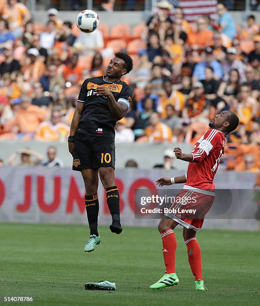 Giles Barnes of Houston Dynamo heads the ball away from Teal Bunbury of New England Revolution at BBVA Compass Stadium on March 6, 2016 in Houston,...