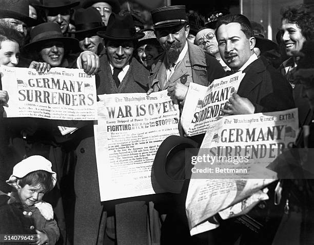 Jubilant Americans in Washington, D.C., show newspaper headlines which announce the surrender of Germany, ending World War I, November 8, 1918.